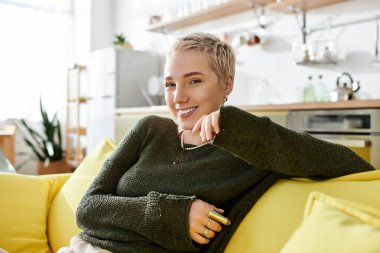 Kısa saçlı genç bir kadın evinde rahatça rahatlar, mutluluk ve sıcaklık saçar..