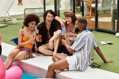 Genç arkadaşlar, neşeli bir parti atmosferinde havuz kenarında eğlenirken kahkaha ve içkinin tadını çıkarıyorlar..