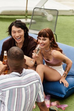 Bir grup genç, şık arkadaş havuz kenarında kahkaha ve içkileri paylaşıyor, birlikte kutluyorlar..