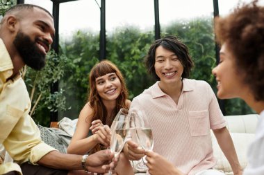 Genç arkadaşlar açık bir kafede içkilerini yudumlarken neşe ve kahkahayı paylaşıyorlar..