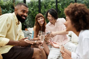 Bir grup genç arkadaş güneşli bir günde açık bir kafede kahkaha ve içki paylaşıyorlar..