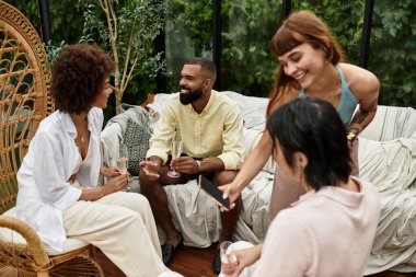 Şık giyinmiş bir grup neşeli arkadaş açık havada neşeli bir kafede mutlu anları paylaşıyorlar.