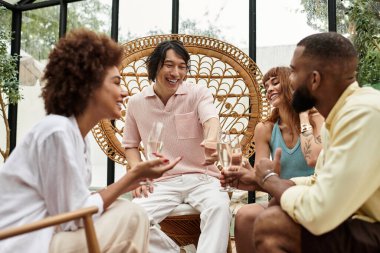 Dört arkadaş gülüyor ve birlikte kadeh kaldırıyorlar. Açık bir kafede. Etrafı yeşilliklerle çevrili..