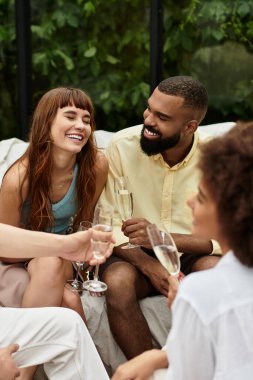 Genç arkadaşlar kahkahalarını ve hikayelerini açık bir kafede köpüklü içkilerini yudumlarken paylaşırlar.