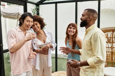 Mutlu arkadaşlar güneşli bir öğleden sonra şık bir açık hava kafede birlikte kahkaha ve içkinin keyfini çıkarırlar..