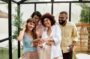 Şık kıyafetler içindeki genç arkadaşlar açık hava kafeteryasında ortak bir deneyimle mutlu mesut kaynaşıyorlar..