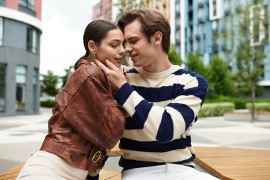Genç çift renkli binalarla çevrili, modaya uygun bir şehir bölgesinde sevgiyle kucaklaşıyor..