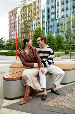 Genç bir çift birbirine yakın oturuyor, yeşillik dolu renkli bir parkta gülücükler ve kahkahalar atıyorlar..