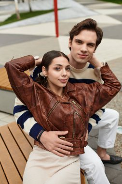 Sevgi dolu çift bir bankta kucaklaşır, şık bir şehir parkında birbirlerine eşlik ederler..