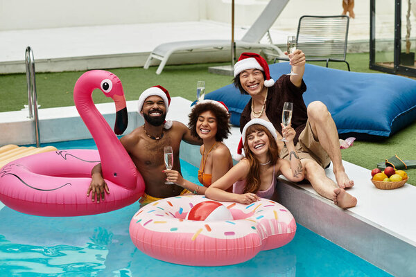 Друзья собираются у солнечного бассейна, радостно празднуя Рождество с напитками и праздничной одеждой.