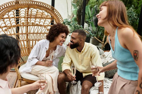 Молодые друзья в стильной одежде делятся смехом и напитками в оживленном кафе.