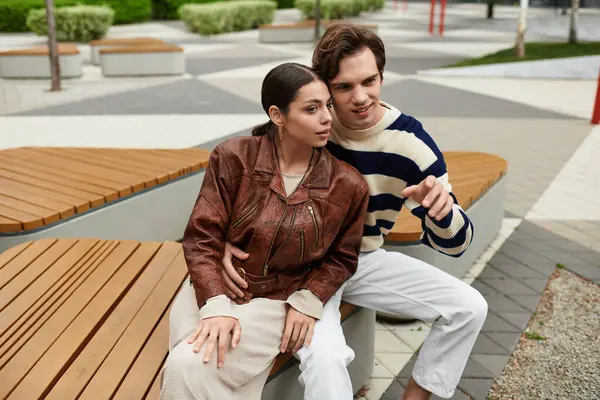 Güneşli bir şehir parkındaki bankta oturan genç bir çift neşeli anlar ve kahkahalar atıyor..