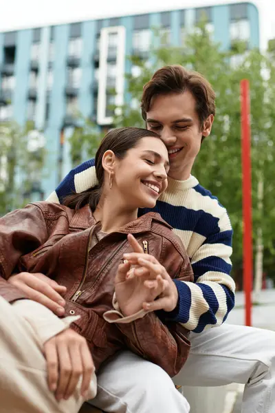 Genç bir çift, canlı bir şehir parkında gülümseyen ve kucaklayan bir anı paylaşıyor..