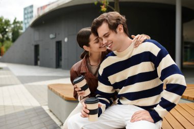 Sevgi dolu bir çift, sıcak bir ortamda kahve yudumlarken kucaklaşır..