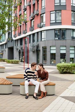 Çağdaş bir parkta birlikte otururken iki genç aşık eğlenceli bir etkileşimi paylaşıyor..