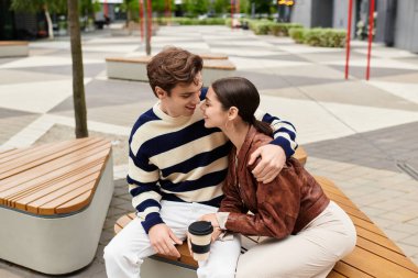 Çift bankta sarılır, usulca güler ve bir şehir parkında birbirlerine eşlik ederler..