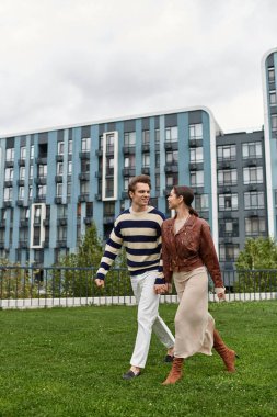 Genç bir çift el ele gezer, hayat dolu bir şehir ortamında birbirlerine gülümserler..