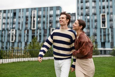 Genç bir çift, sevgi ve mutluluk saçan yemyeşil bir parkta el ele yürür..