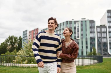 Genç bir çift yeşillik dolu bir parkta yürürken birbirlerine eşlik etmekten zevk alır..