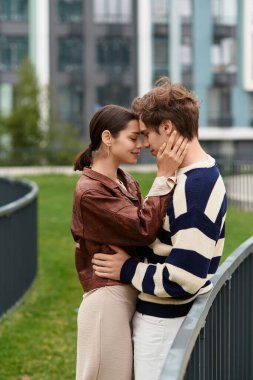 Aşka sarılmış genç bir çift, canlı bir şehir parkında bir anlık bağlantının tadını çıkarıyor..