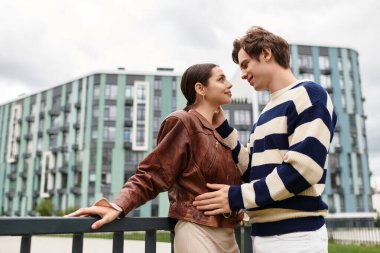 Genç bir çift birbirlerine sevgiyle gülümsüyor, şehrin içinde güzel bir anın tadını çıkarıyorlar..
