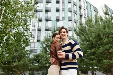 Sevgi dolu çift dışarıda kucaklaşır, şık bir şehir ortamında birbirlerine eşlik ederek eğlenirler..