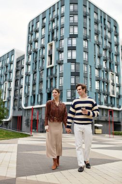 Neşeli genç bir çift çağdaş bir mahallede el ele yürür, sevgi saçar..