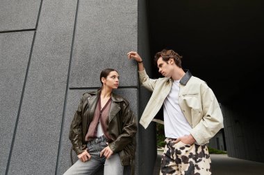 İki genç aşık, modern bir açık hava ortamında sıcak ve sevgi dolu bakışlarını paylaşıyor..