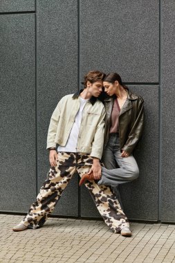 Sevgi dolu çift, dokulu bir duvara yaslanır, derin bir bağ ve açık havada sevgi ifade eder..