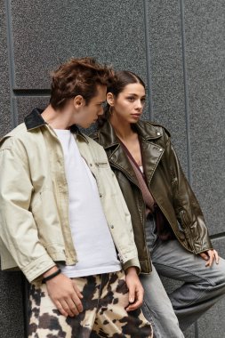 Genç bir çift, modern bir duvara yaslanmış hassas bir anı paylaşıyor..