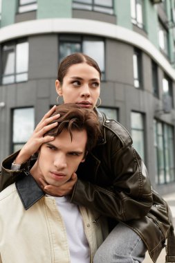 Genç bir çift, modern bir binanın önünde, romantizm ve yakınlıklarını sergiliyor..