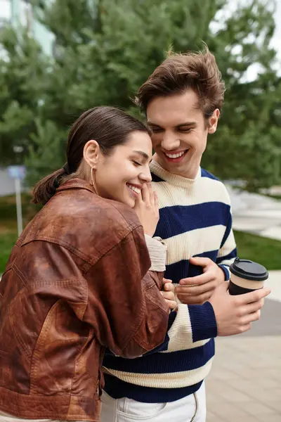 İki genç aşık, doğal ortamlarında kahvelerini yudumlarken mutlu bir kucaklaşmayı paylaşıyorlar..