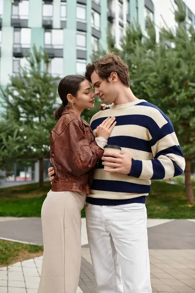 Sevgi dolu bir çift, çağdaş bir şehir ortamında yeşilliklerle çevrili bir şekilde sıcak bir şekilde kucaklaşır..