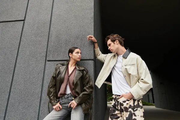 İki genç aşık, modern bir açık hava ortamında sıcak ve sevgi dolu bakışlarını paylaşıyor..