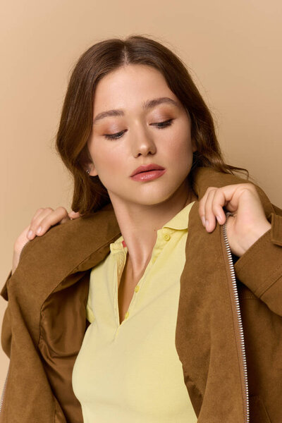 A young woman confidently poses in a yellow outfit and brown jacket, exuding autumn vibes.
