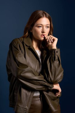 Genç bir kadın, sonbahar modasını şık kahverengi deri bir elbiseyle zarifçe poz vererek sergiliyor..