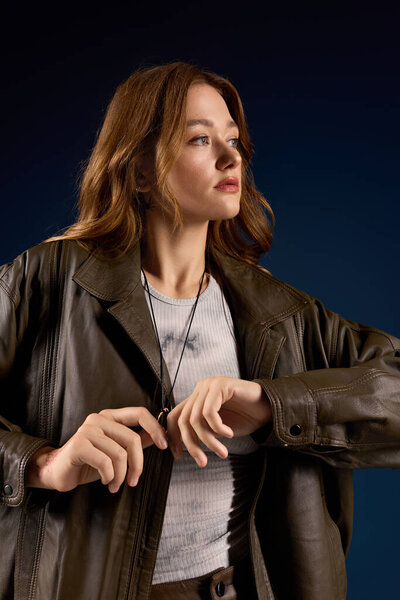 Молодая женщина изящно позирует в коричневом кожаном ансамбле на ярком синем фоне.
