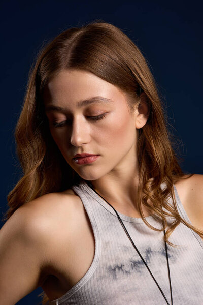 Молодая женщина элегантно позирует в коричневой кожаной одежде на ярко-голубом фоне.