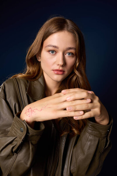 Красивая молодая женщина демонстрирует осеннюю моду в шикарном коричневом костюме из кожи на синем фоне.