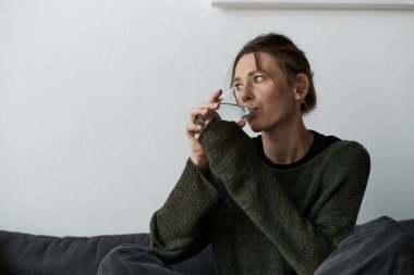 Genç bir kadın kendini evde düşüncelere dalmış, suyunu yudumlarken ve hayatı düşünürken buluyor..