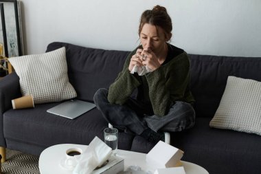 Etrafı peçete ve kahveyle çevrili bir kadın, düşüncelerinde kaybolmuş ve duygularıyla savaşıyor..