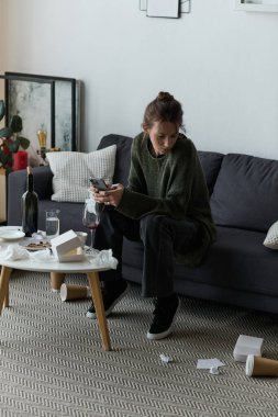 Genç bir kadın kanepede oturur, kendini kaybolmuş ve etrafı dağınık hisseder..