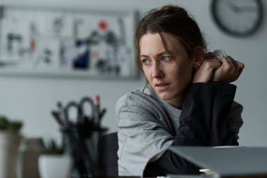 Genç bir kadın evinde sessizce oturur, düşüncelere dalmış ve duygularının ağırlığını hisseder..