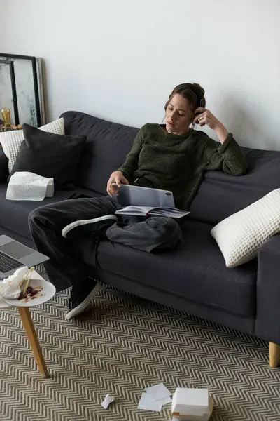 Genç bir kadın kanepesinde oturuyor. Dağınık bir yaşam alanının ortasında, düşüncelere dalmış olarak..