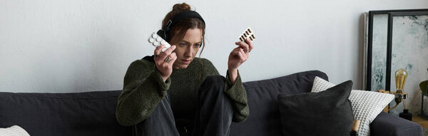 В тихой гостиной молодая женщина сжимает свои лекарства, чувствуя депрессию..