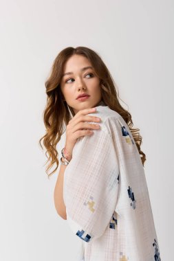 Genç bir kadın kendine güvenerek poz veriyor, güzelliğini ve çekiciliğini ön plana çıkaran modaya uygun bir kıyafet giyiyor..