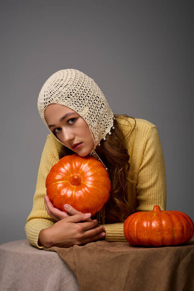 Young woman in stylish outfit poses with pumpkins, capturing the essence of autumn fashion.