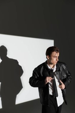 Deri ceketli genç adam, modaya uygun bir stüdyoda gençlik kültürü sergiliyor..