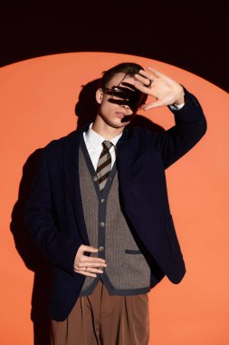 Genç yakışıklı adam ışık ve gölgelerle oynarken moda sergiliyor..