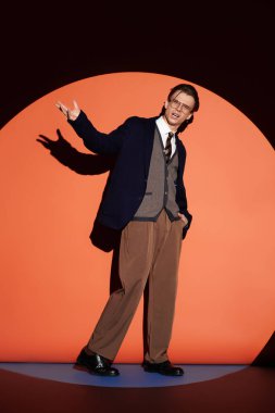 Yakışıklı genç adam cesur turuncu bir arka plana karşı durarak gençlik kültürünü ifade ediyor..